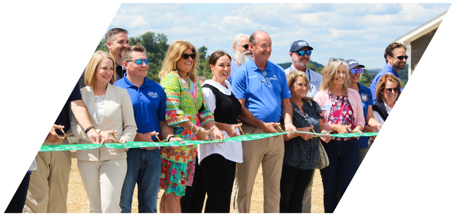 Adults holding a ribbon at a ribbon cutting.